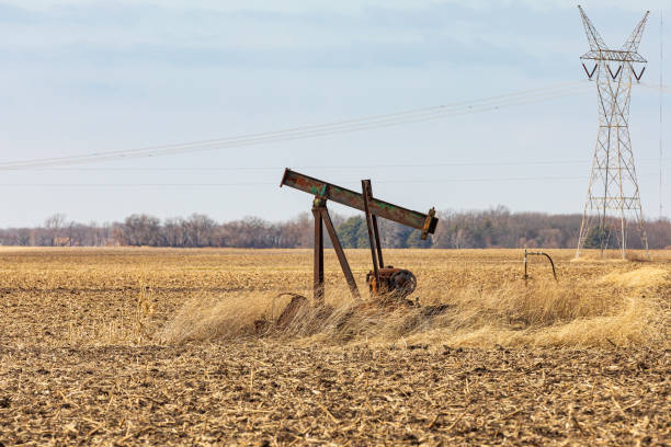 Old, orphaned oil well pump in farm field Old, orphaned oil well pump in farm field